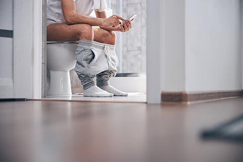 Man using his gadget in the water closet