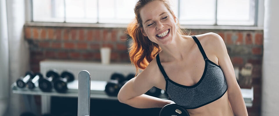 Laughing vivacious young woman in a gym