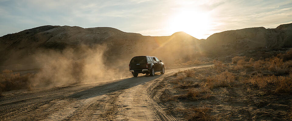 Concept travel offroad with car 4x4. A black pickup truck is climbing uphill on a dirt road.