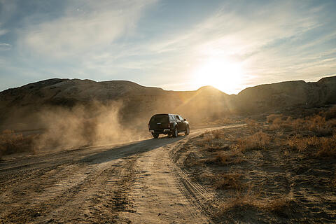 Concept travel offroad with car 4x4. A black pickup truck is climbing uphill on a dirt road.